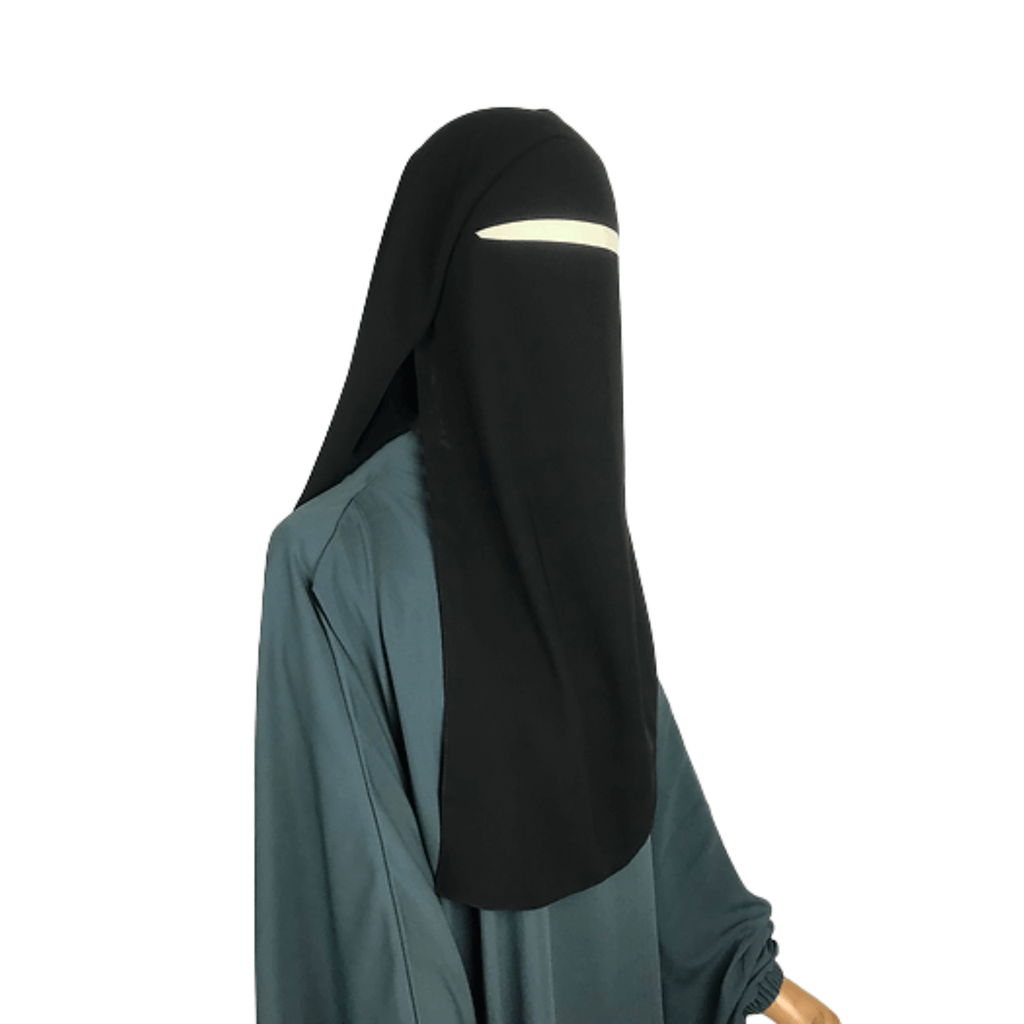 Person wearing a black niqab and green dress on a white background